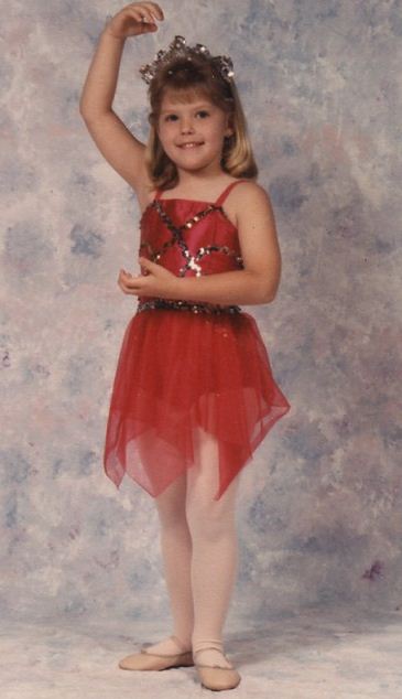 A little girl in red dress standing on one leg