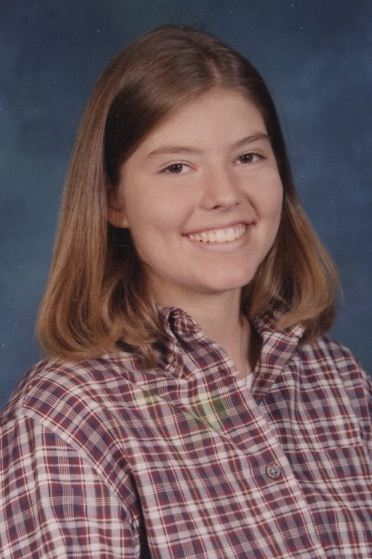 A young woman in plaid shirt smiling for the camera