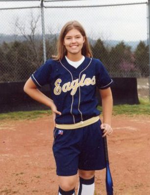 A girl in blue and white baseball uniform holding a bat
