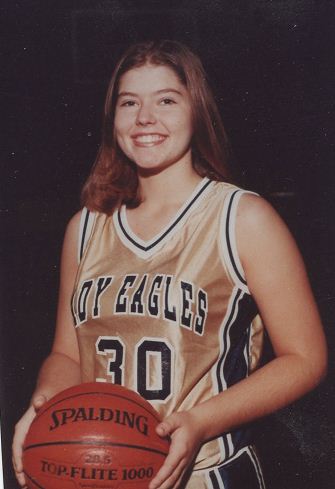 A young girl holding onto a basketball in her uniform