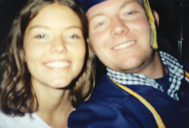 A man and woman in graduation attire smiling for the camera