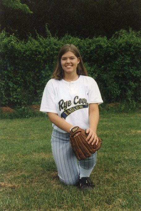 A woman in baseball uniform holding a catcher's mitt