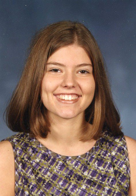 A woman with long hair and a dress smiles